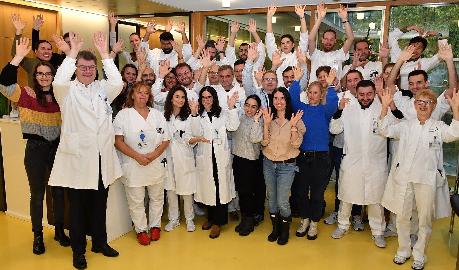 Ärzte, Chirurgen und Mitarbeiter der Herzchirurgie heben die Hände nach oben und lachen